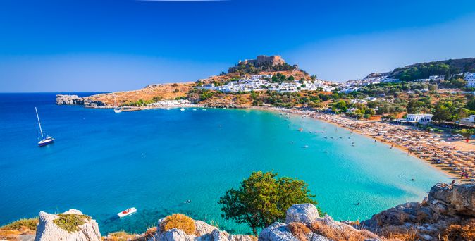 Bucht in Griechenland mit Strand und einer Stadt im Hintergrund