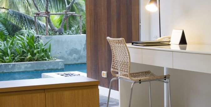 Ein Hotelzimmer mit Schreibtisch, im Hintergrund ein Swim-up Pool