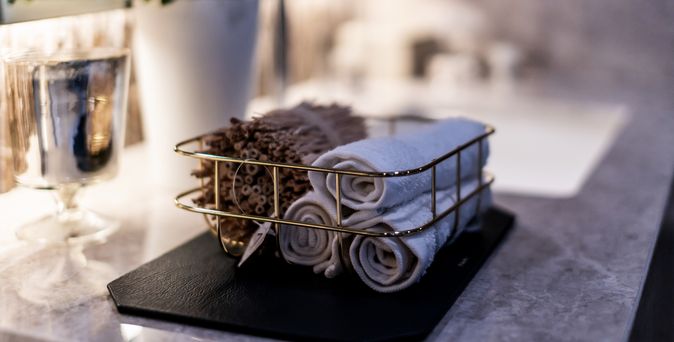 In einem Korb liegen zusammengerollte Handtücher und ein Bündel Duftstäbe