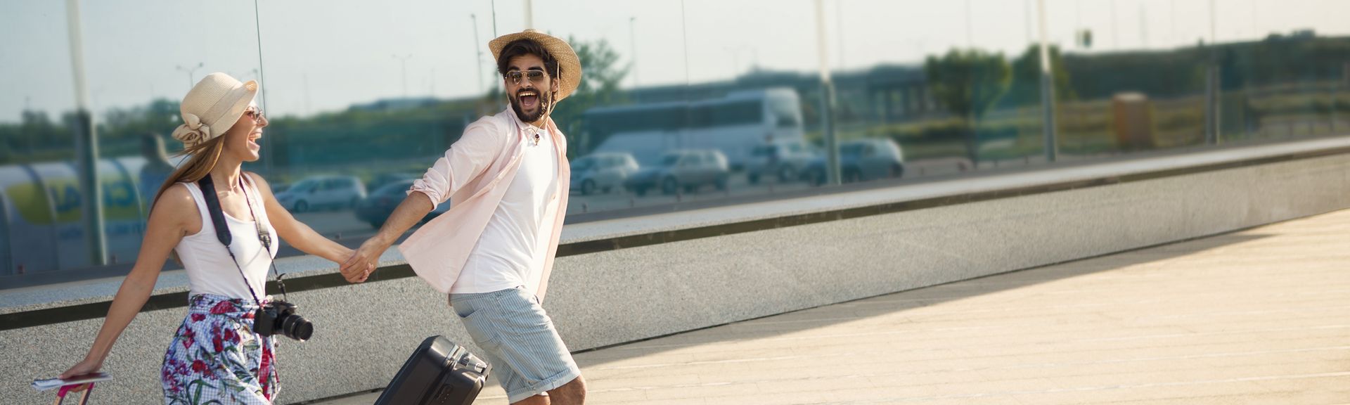 Ein Paar läuft mit Koffern aufgeregt einen Weg entlang