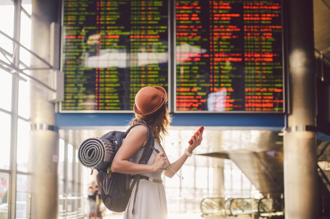 Alleinreisende Frau schaut auf einen Zeitplan am Bahnhof