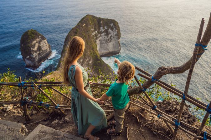 Mutter und Kind schauen von einer Treppe aus auf das Meer