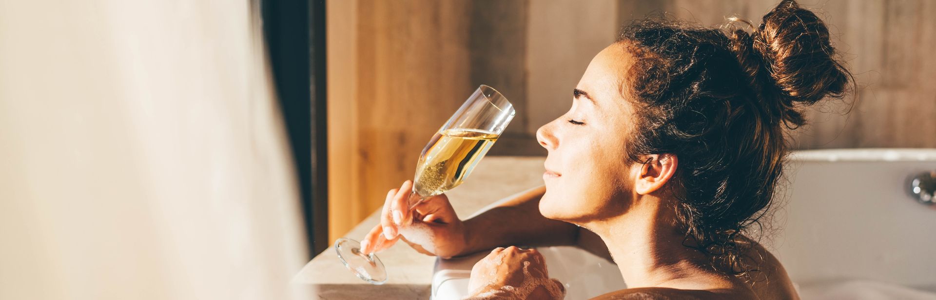 Eine Frau lehnt am Rand eines Whirlpools und genießt ein Glas Sekt