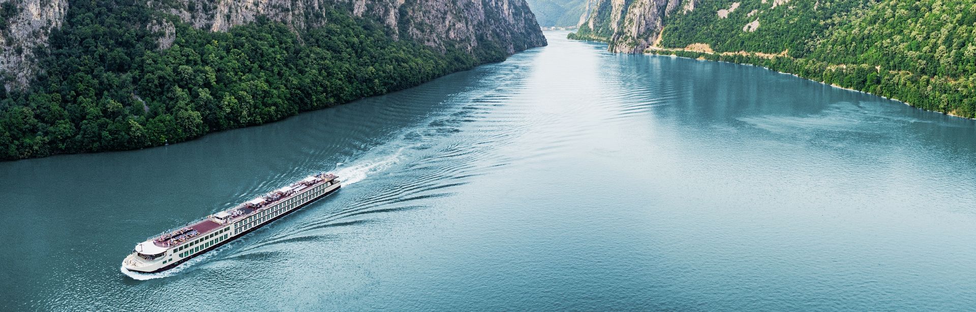 Flusskreuzfahrschiff fährt durch einen Fluss, umgeben von steilen Klippen