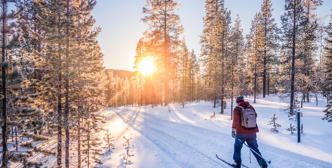 Mann auf Skiern läuft durch eine Schneelandschaft
