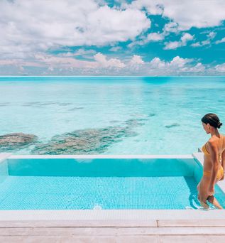 Eine Frau steigt in einen erhöht über dem Strand gelegen Pool
