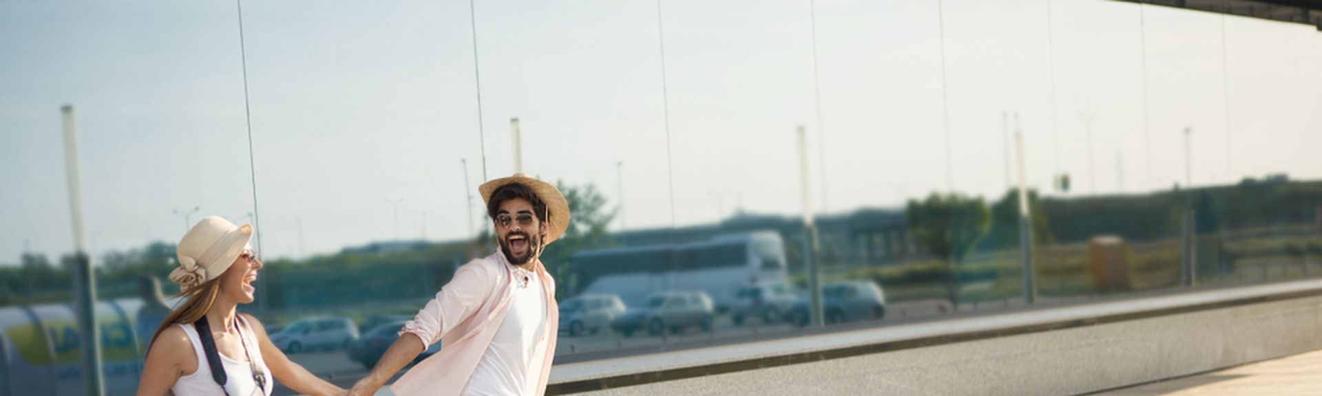 Ein Paar läuft mit Koffern aufgeregt einen Weg entlang