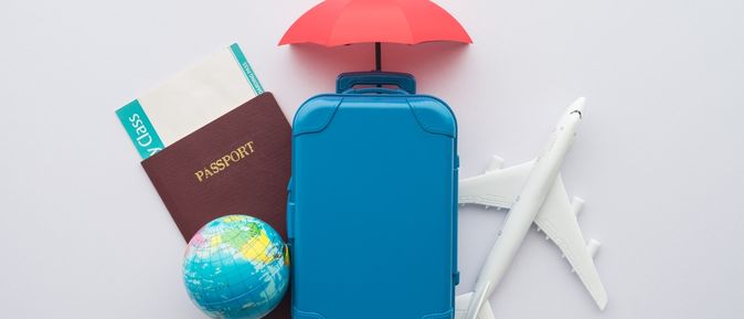 Ein Reisepass mit Flugticket, ein Miniaturkoffer, Flugzeug und eine Weltkugel