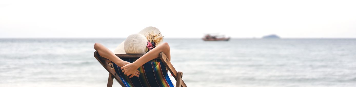 Person am Strand auf einer Liege schaut auf das Meer