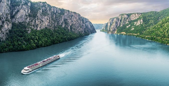 Flusskreuzfahrschiff fährt durch einen Fluss, umgeben von steilen Klippen