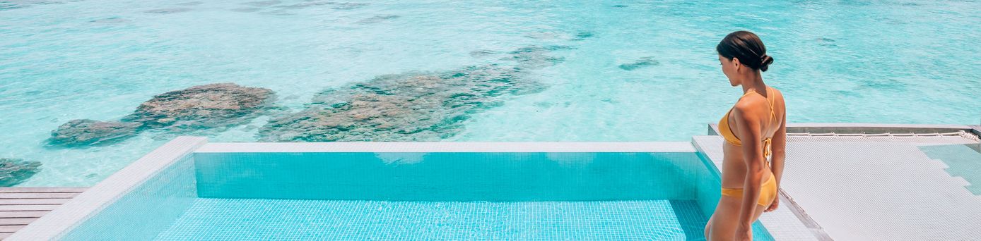 Eine Frau steigt in einen erhöht über dem Strand gelegen Pool
