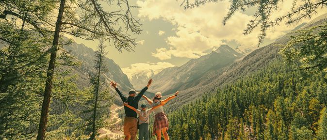 Eltern und Kind schauen beim Wandern gemeinsam auf eine Berglandschaft 