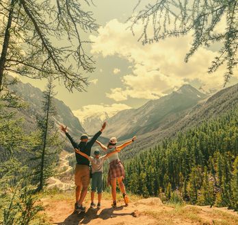 Eltern und Kind schauen beim Wandern gemeinsam auf eine Berglandschaft 