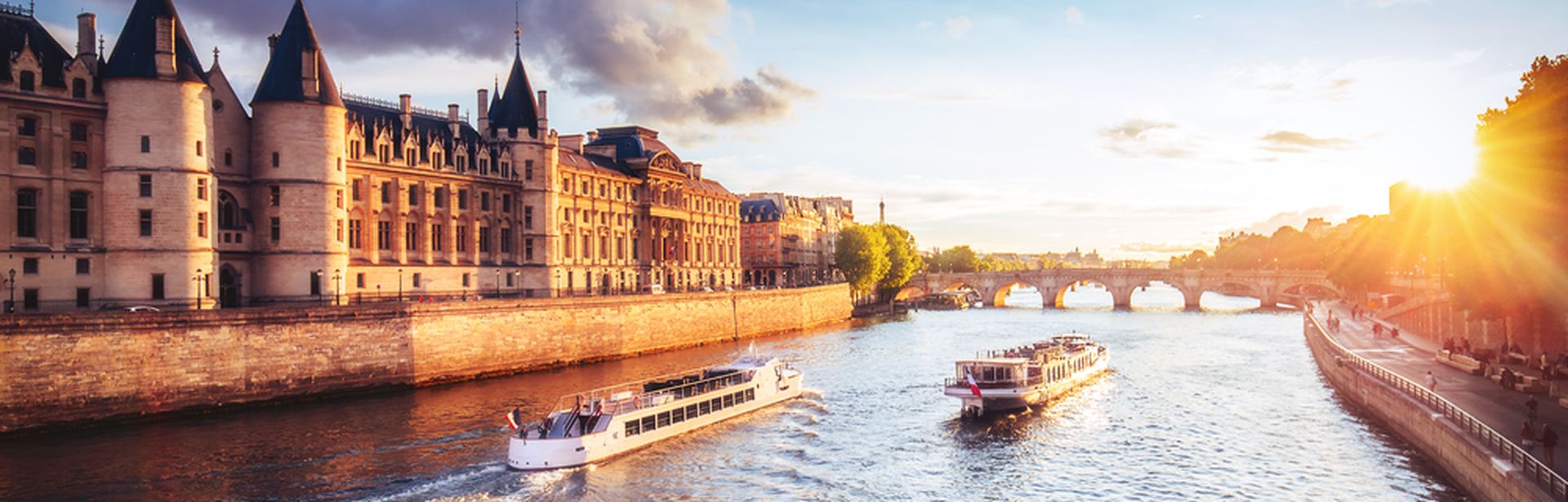 Zwei Flusskreuzfahrschiffe fahren an einer Burg entlang bei Sonnenuntergang
