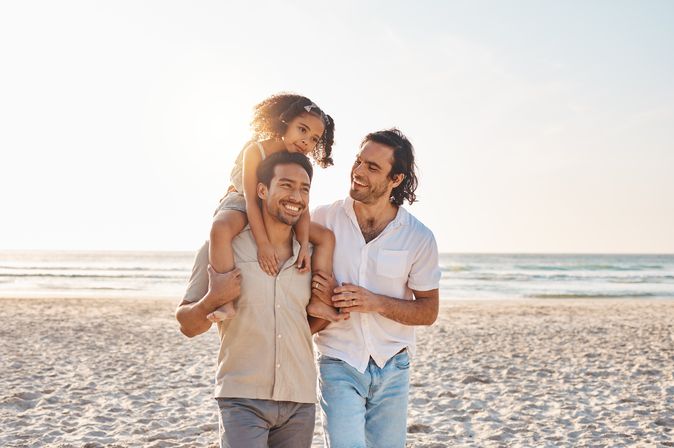 Eine Familie am Strand, Tochter sitzt auf den Schultern des Vaters