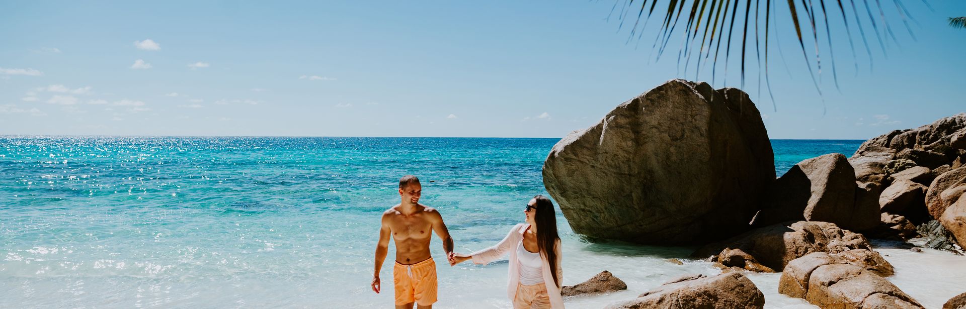 Paar läuft händchenhaltend am Strand entlang