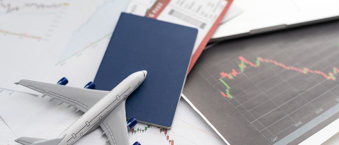 Ein Spielzeugflugzeug liegt mit einem Reisepass und einem Flugticket auf dem Tisch