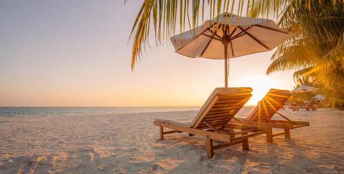 Zwei Liegen unter einem Schirm am Strand