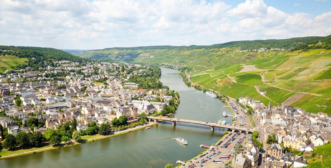 Fluss mit Brücke, die zwei Seiten eines Dorfes inmitten einer grünen Landschaft verbindet