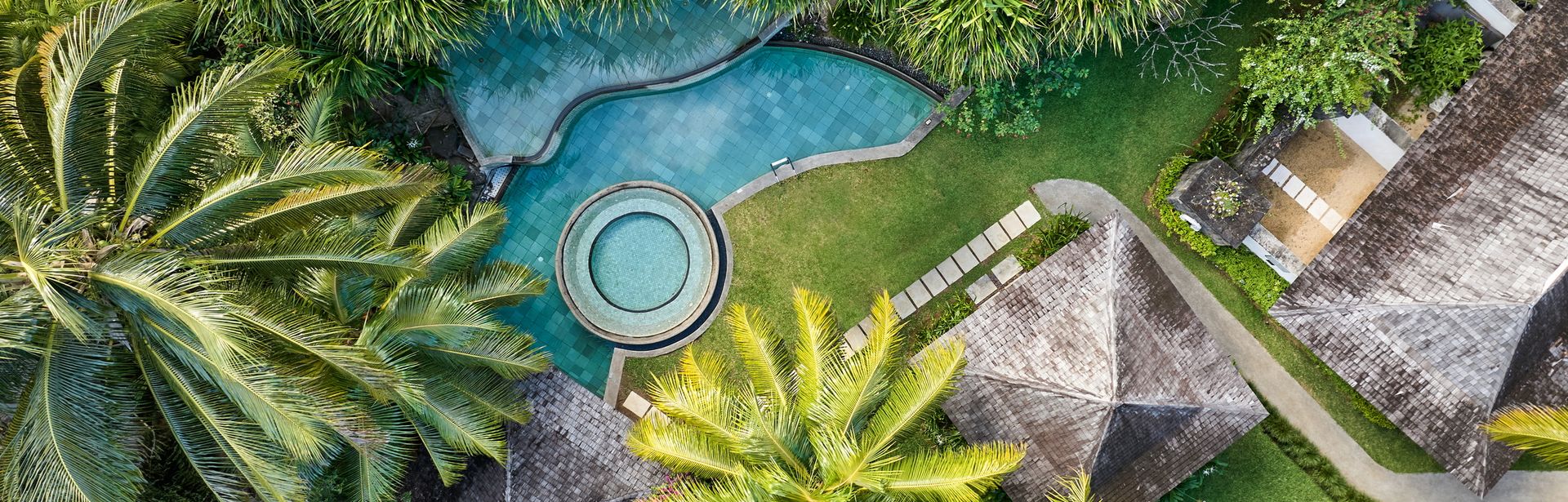 Privatpools einer Ferienhausanlage umgeben von Palmen