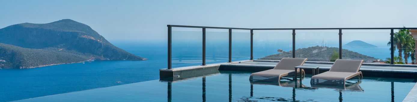 Infinity Pool mit zwei Liegen und dem Meer im Hintergrund