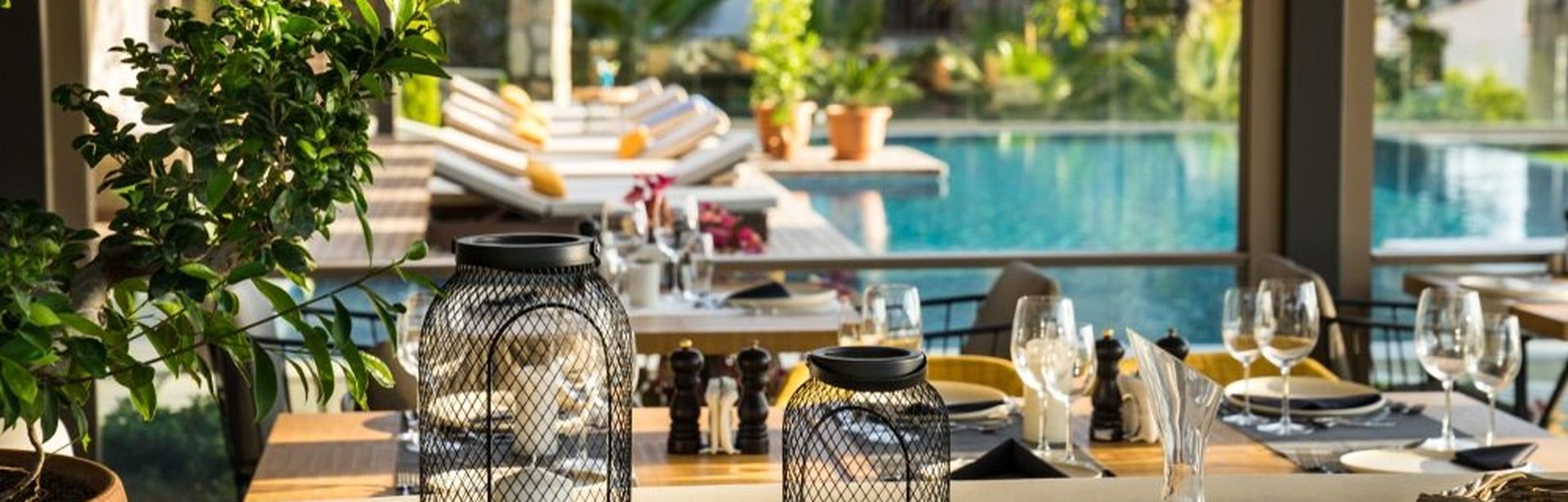 Kerzen und Gläser auf einer Theke mit Poolbereich im Hintergrund