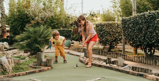 Junge und Mädchen spielen gemeinsam Minigolf