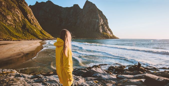 Eine Frau in einer gelben Regenjacke schaut auf das Meer