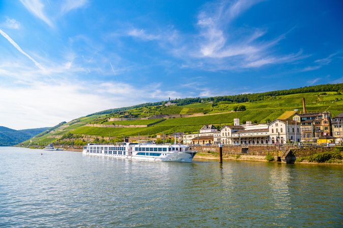 Flusskreuzfahrtschiff auf einem Fluss, der durch eine grüne Landschaft führt