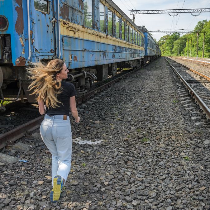 Frau läuft zu einem Zug zwischen den Gleisen