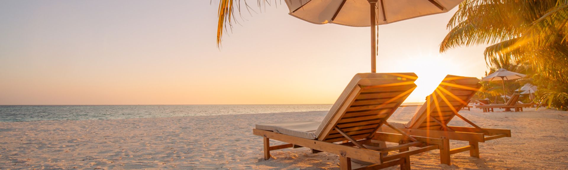 Zwei Liegen unter einem Schirm am Strand