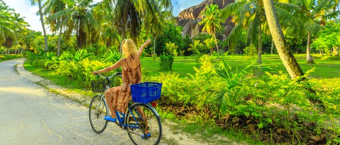 Eine Frau fährt einhändig Fahrrad durch eine grüne Landschaft
