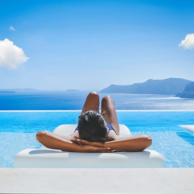 Eine Frau liegt auf einer Liege im Pool mit Blick auf das Meer