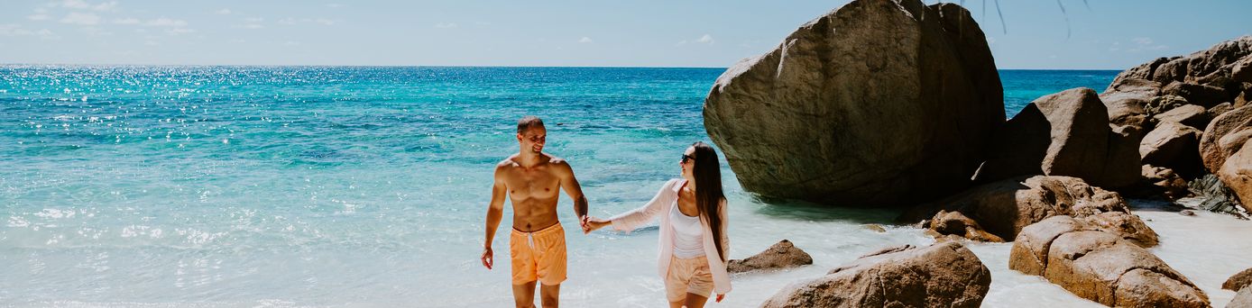 Paar läuft händchen haltend am Strand entlang