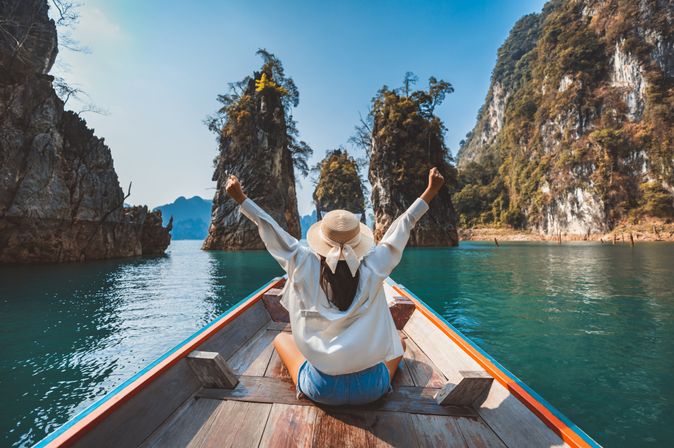Alleinreisende Frau in einem Boot auf dem Wasser in Thailand