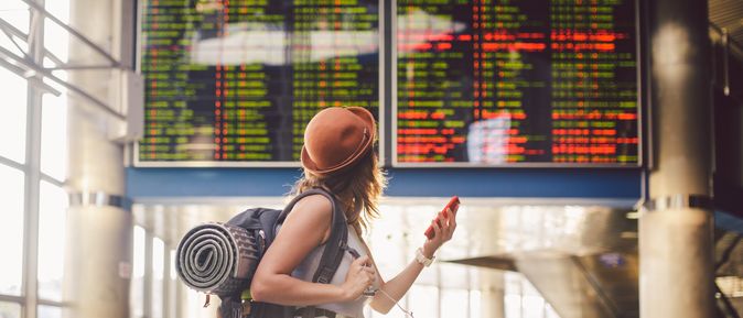 Alleinreisende Frau schaut auf einen Zeitplan am Bahnhof