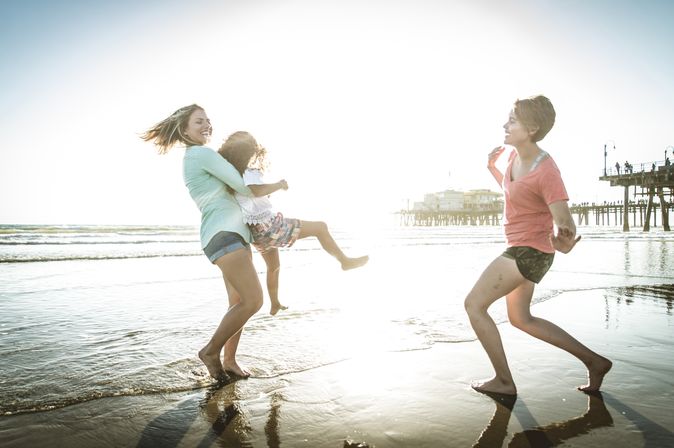 Eine Familie am Strand, Mutter hebt Ihre Tochter lachend hoch