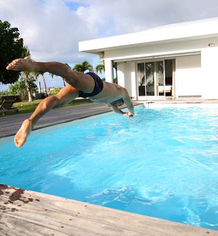 Ein Mann springt Kopfüber in einen großen privaten Pool