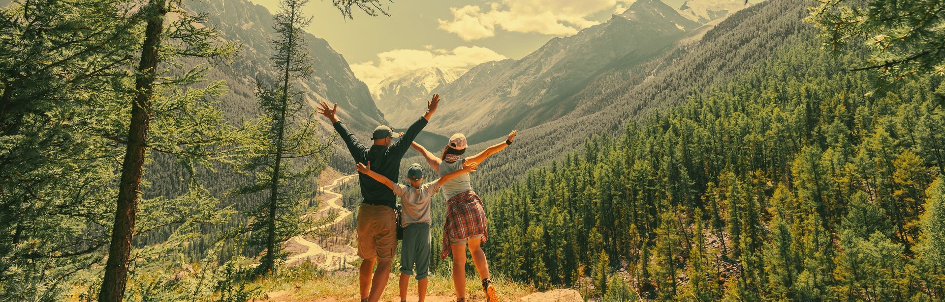 Eltern und Kind schauen beim Wandern gemeinsam auf eine Berglandschaft 