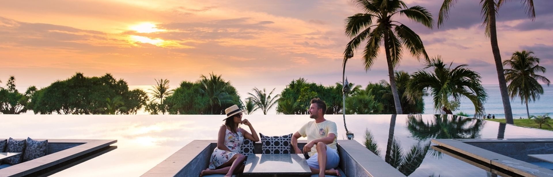 Ein Mann und eine Frau sitzen bei Sonnenuntergang in einer trockenen Sitzecke, die sich in einem Pool befindet