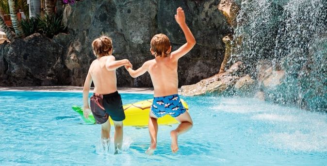 Zwei Jungs springen in einen Pool