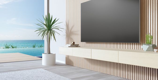 Fernseher in einem Hotelzimmer. Im Hintergrund ist ein Pool und das Meer zu sehen