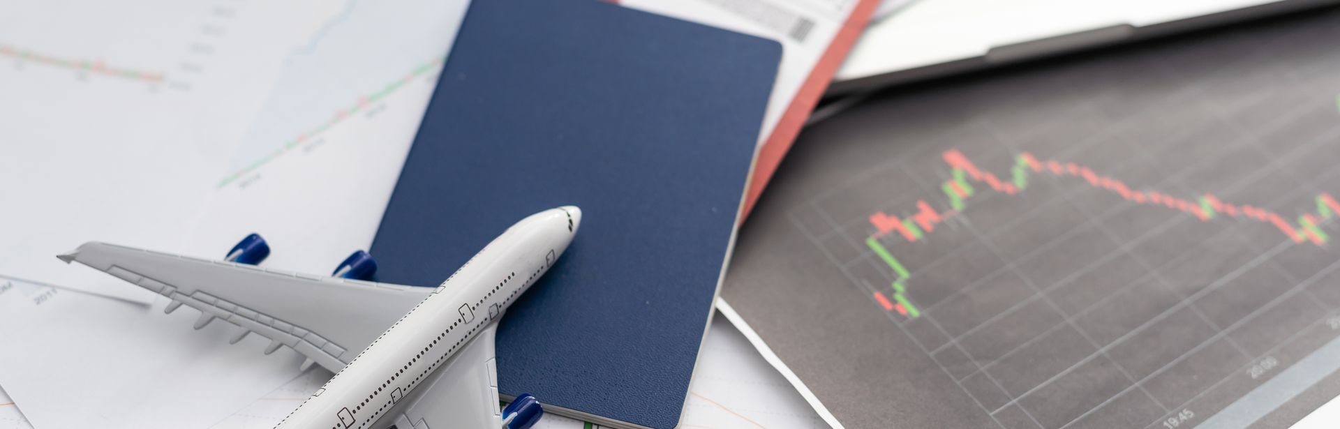 Ein Spielzeugflugzeug liegt mit einem Reisepass und einem Flugticket auf dem Tisch