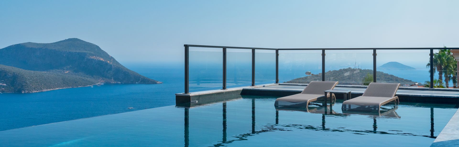 Infinity Pool mit zwei Liegen und dem Meer im Hintergrund