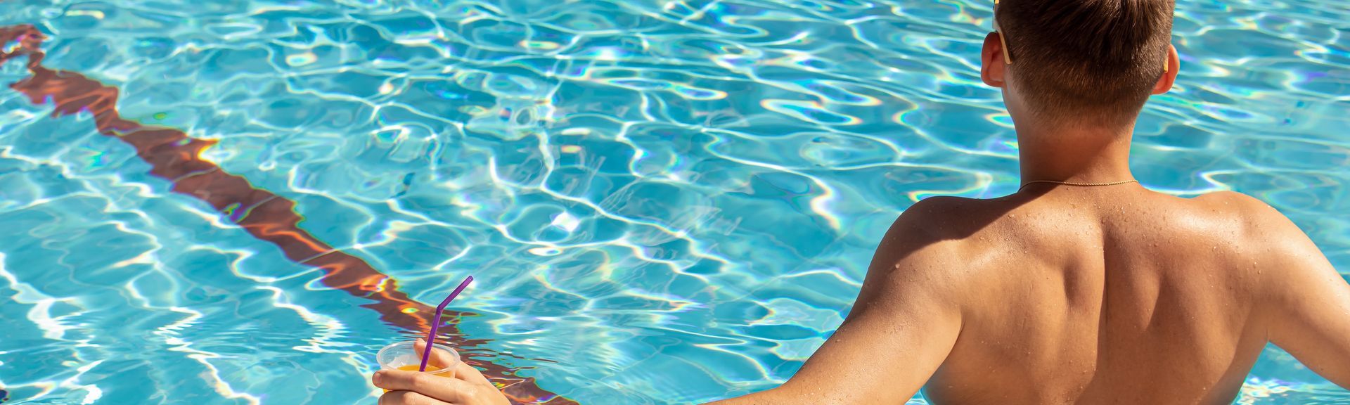 Mann mit Getränk in der Hand sitzt im Pool