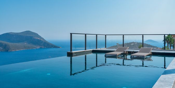 Infinity Pool mit zwei Liegen und dem Meer im Hintergrund