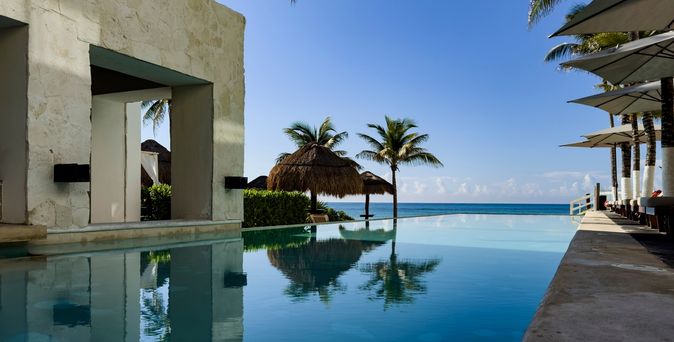 Ein Pool umgeben von Palmen und mit Blick auf das Meer