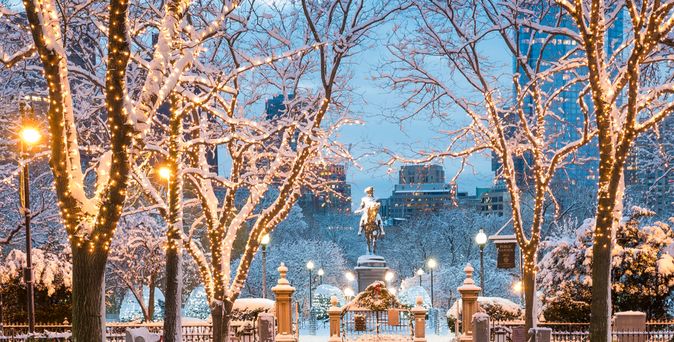 Beleuchteter Weg zu einer Statue im Winter, während Schnee liegt