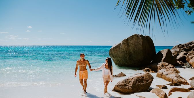 Paar läuft händchen haltend am Strand entlang