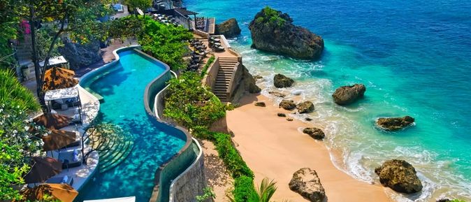 Infinity-Pool auf einer Terrasse oberhalb des Strandes. Unterhalb führt eine Treppe direkt zum Meer